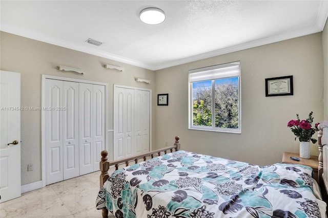 bedroom with crown molding and two closets