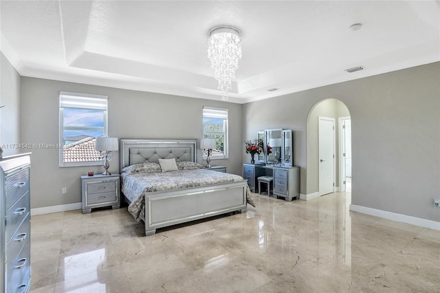 bedroom with an inviting chandelier, a tray ceiling, and crown molding