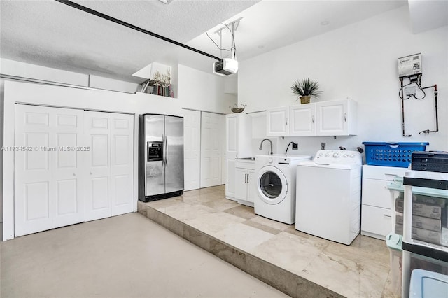 laundry area featuring sink, washer and clothes dryer, cabinets, and a textured ceiling