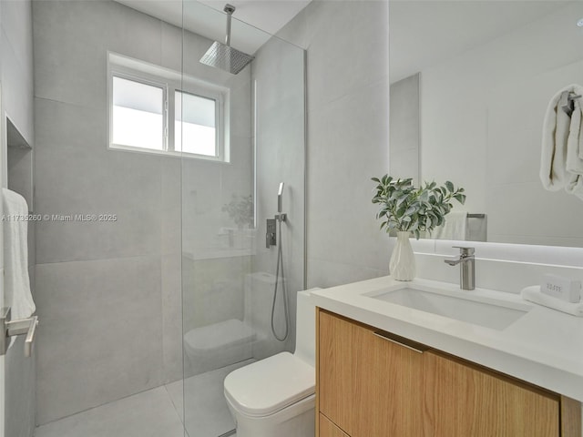 bathroom featuring tiled shower, tile patterned floors, toilet, tile walls, and vanity