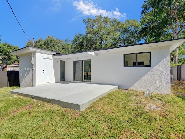 rear view of property with a patio, a yard, and central AC