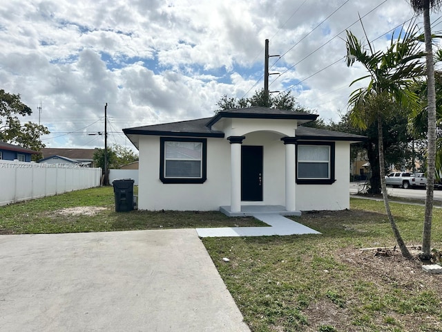 bungalow-style home with a front yard, fence, and stucco siding