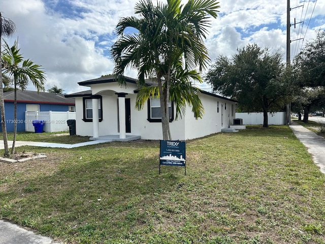 view of front of house featuring a front lawn, fence, and stucco siding