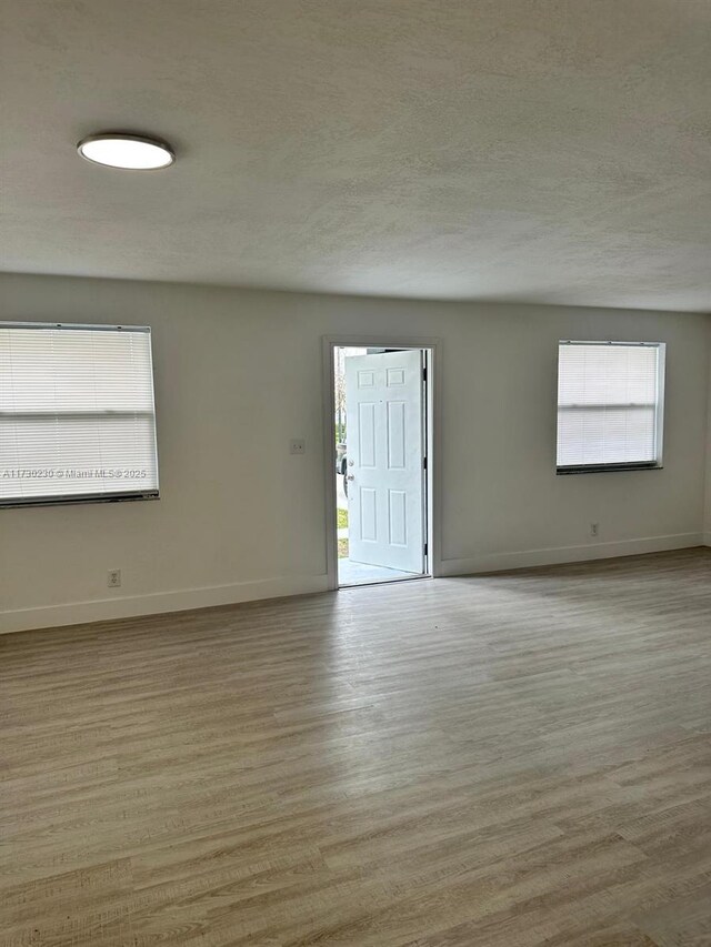 spare room with light hardwood / wood-style floors and a textured ceiling