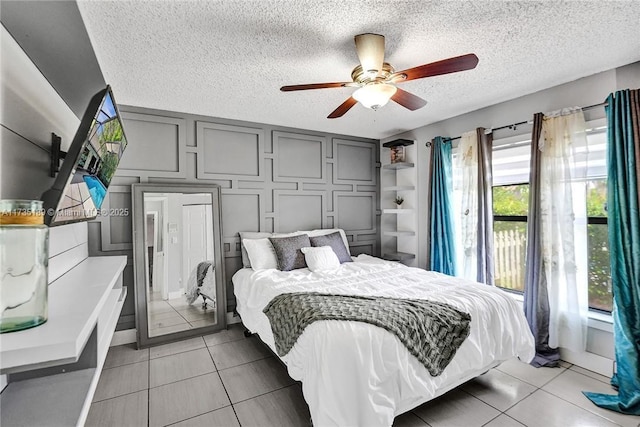 bedroom featuring ceiling fan, tile patterned floors, and a textured ceiling