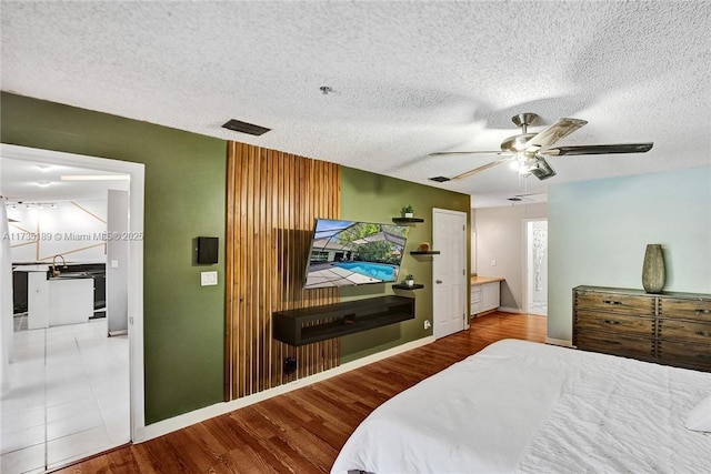 bedroom with ceiling fan, light hardwood / wood-style floors, and a textured ceiling