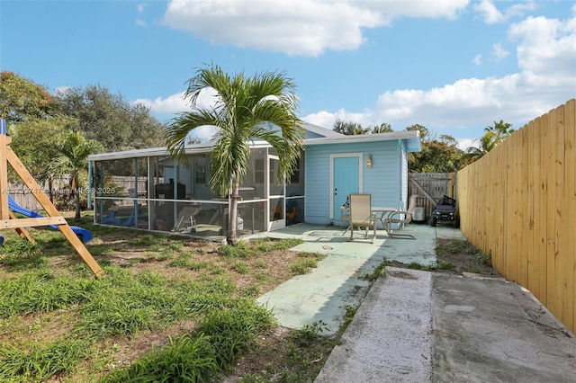 back of property with a patio, a playground, and a sunroom