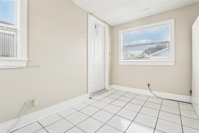 unfurnished room with a paneled ceiling and light tile patterned floors