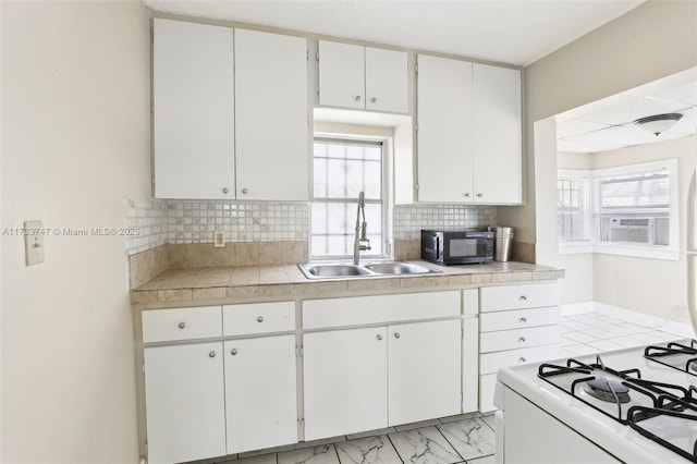 kitchen with tasteful backsplash, white cabinetry, sink, and a wealth of natural light