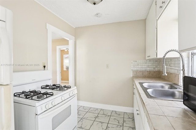 kitchen with sink, white gas range oven, white cabinetry, tasteful backsplash, and tile countertops