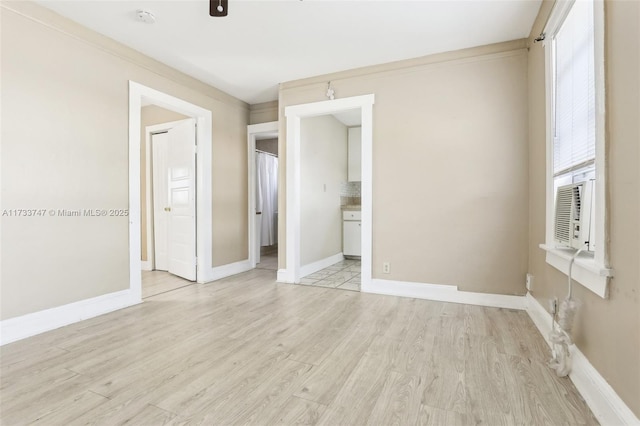 unfurnished bedroom featuring cooling unit, connected bathroom, and light hardwood / wood-style flooring