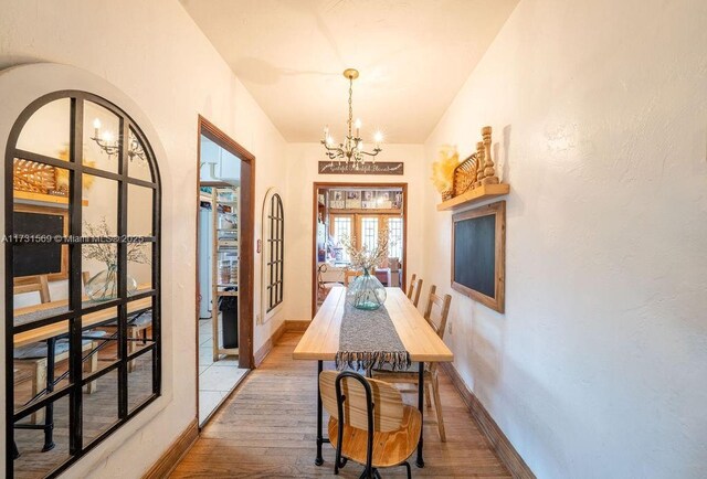 dining area with an inviting chandelier, hardwood / wood-style floors, and french doors