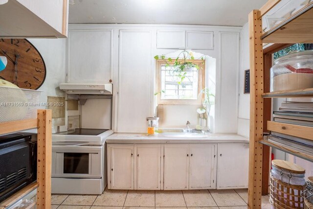 kitchen featuring range with electric stovetop, white cabinetry, and light tile patterned floors