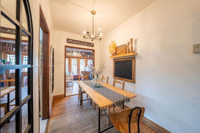 dining room with hardwood / wood-style flooring, french doors, and a notable chandelier