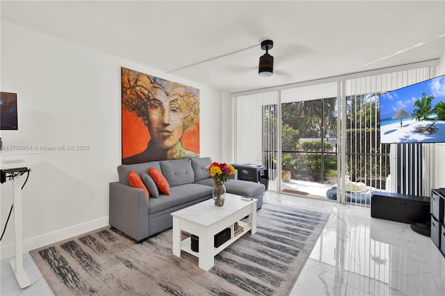 living room featuring ceiling fan and a wall of windows