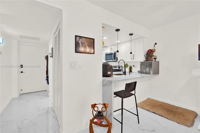 kitchen with pendant lighting, sink, a breakfast bar area, white cabinets, and kitchen peninsula