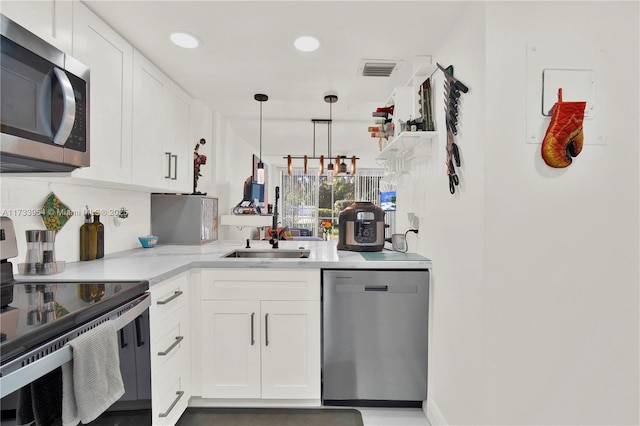 kitchen with sink, light stone counters, hanging light fixtures, stainless steel appliances, and white cabinets