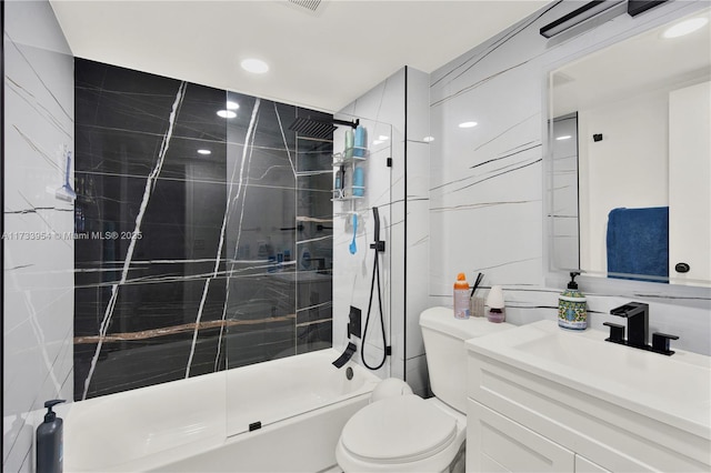 bathroom featuring a tile shower, tile walls, vanity, and toilet