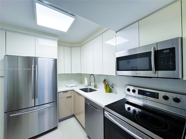 kitchen featuring stainless steel appliances, sink, and light tile patterned floors