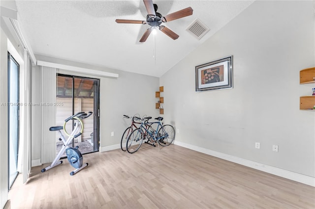 workout area with vaulted ceiling, ceiling fan, a textured ceiling, and light hardwood / wood-style floors