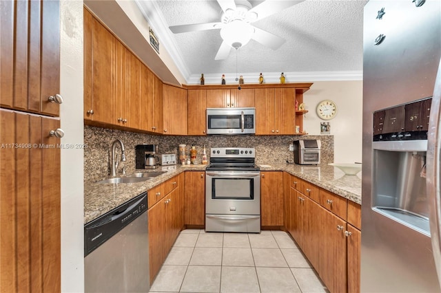 kitchen with sink, a textured ceiling, light tile patterned floors, stainless steel appliances, and light stone countertops