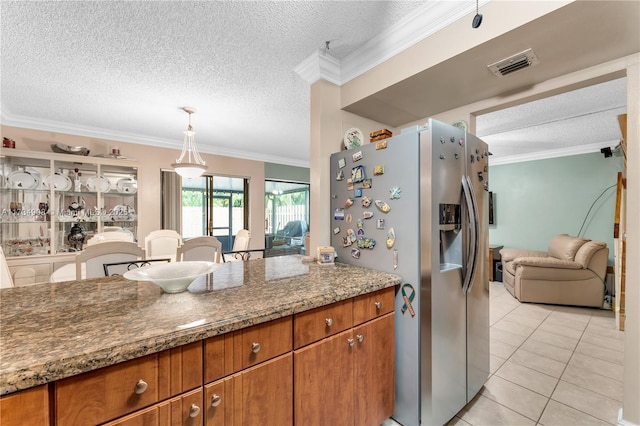 kitchen with crown molding, decorative light fixtures, dark stone countertops, and stainless steel refrigerator with ice dispenser