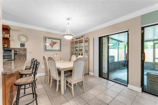 dining area with light tile patterned floors, ornamental molding, and a textured ceiling