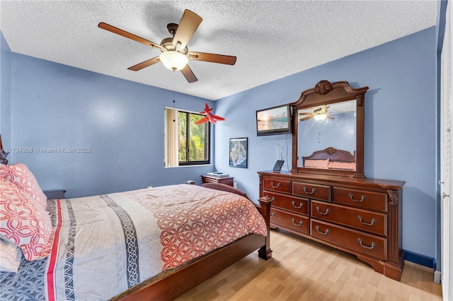 bedroom with ceiling fan, a textured ceiling, and light hardwood / wood-style floors