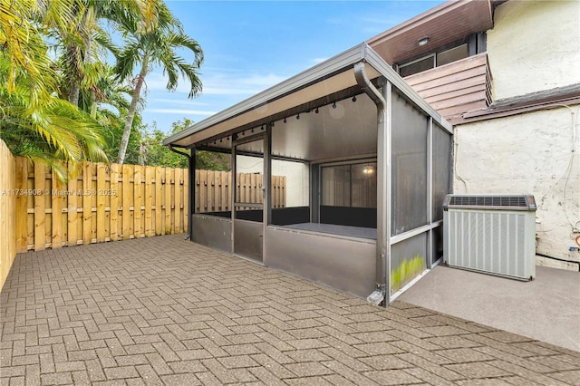 view of property exterior with a sunroom, cooling unit, and a patio area