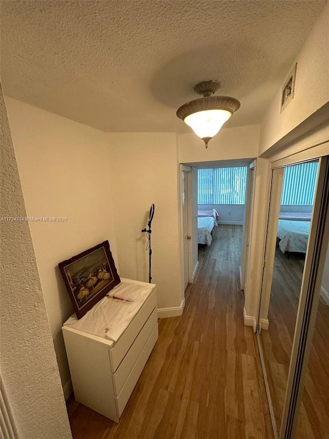 hall with hardwood / wood-style flooring, washer / dryer, and a textured ceiling