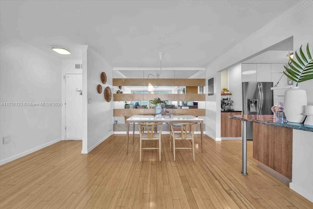 dining room with crown molding and light hardwood / wood-style floors