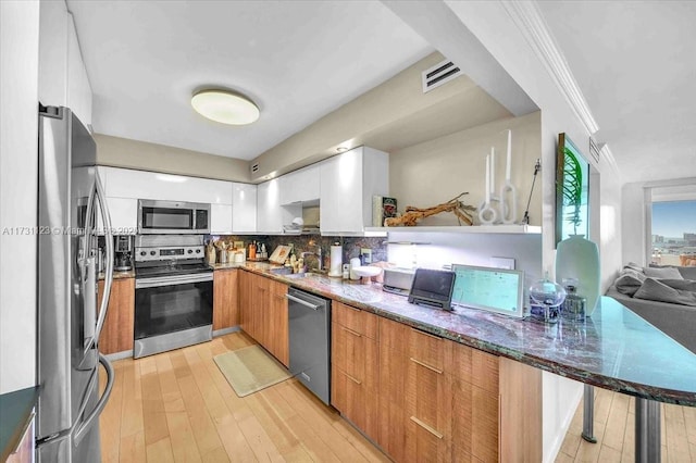 kitchen featuring appliances with stainless steel finishes, tasteful backsplash, sink, dark stone countertops, and white cabinets