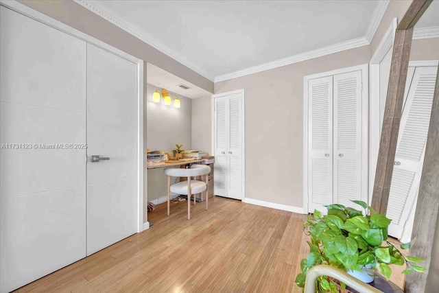 interior space with crown molding, light hardwood / wood-style flooring, and two closets