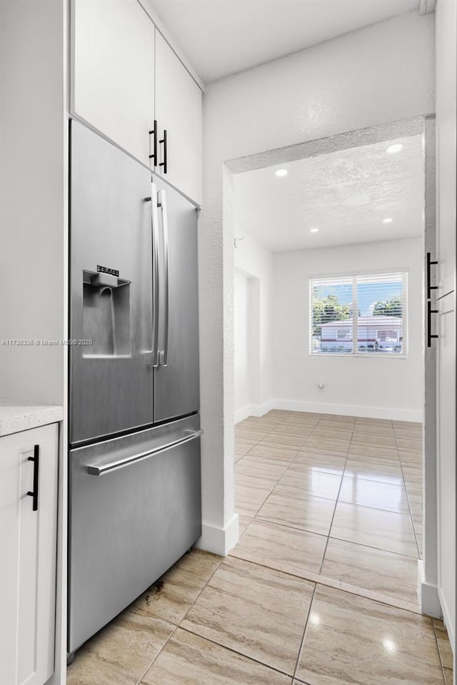 kitchen with a textured ceiling, white cabinets, and stainless steel built in refrigerator