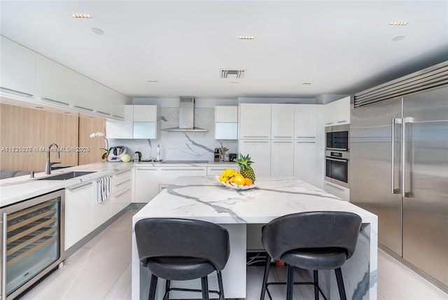 kitchen with wine cooler, wall chimney exhaust hood, sink, white cabinetry, and stainless steel appliances