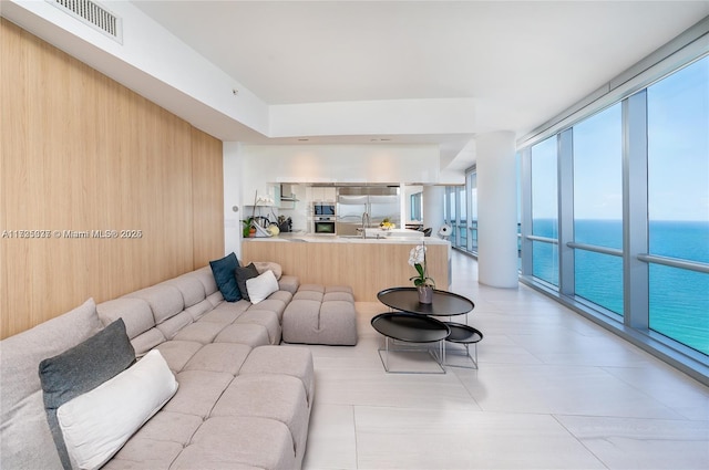 living room with a water view, sink, and a wall of windows