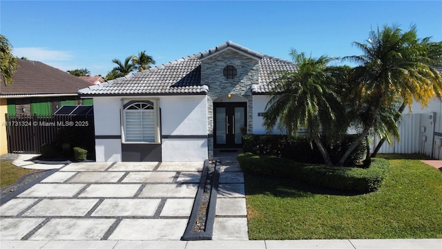 view of front of house featuring a tiled roof, french doors, fence, and stucco siding