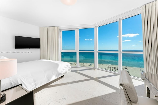 bedroom featuring a water view, expansive windows, and a view of the beach