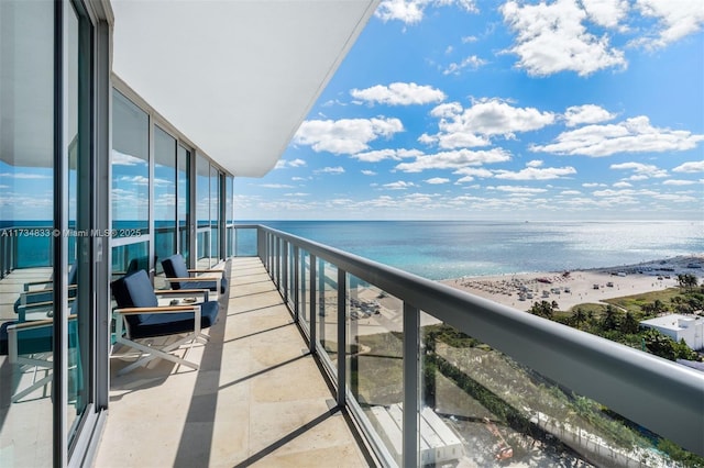 balcony with a water view and a view of the beach