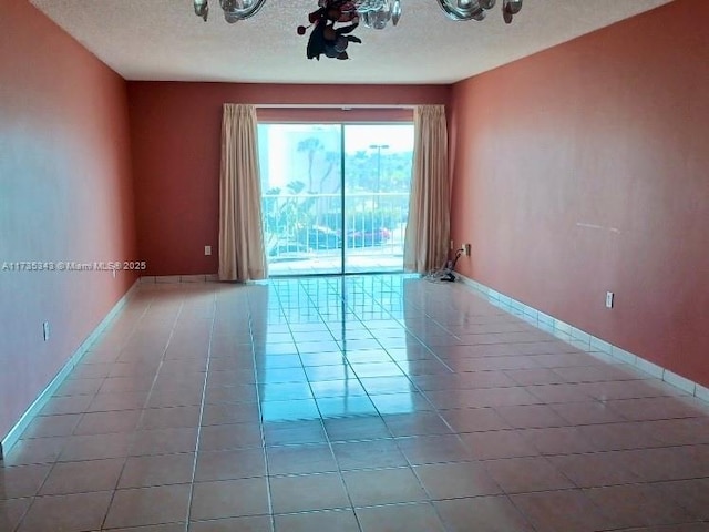 spare room featuring light tile patterned floors and a textured ceiling