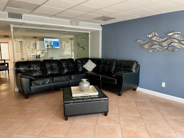 living room with a paneled ceiling and light tile patterned floors