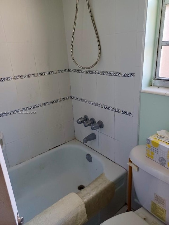 bathroom with tiled shower / bath combo and toilet