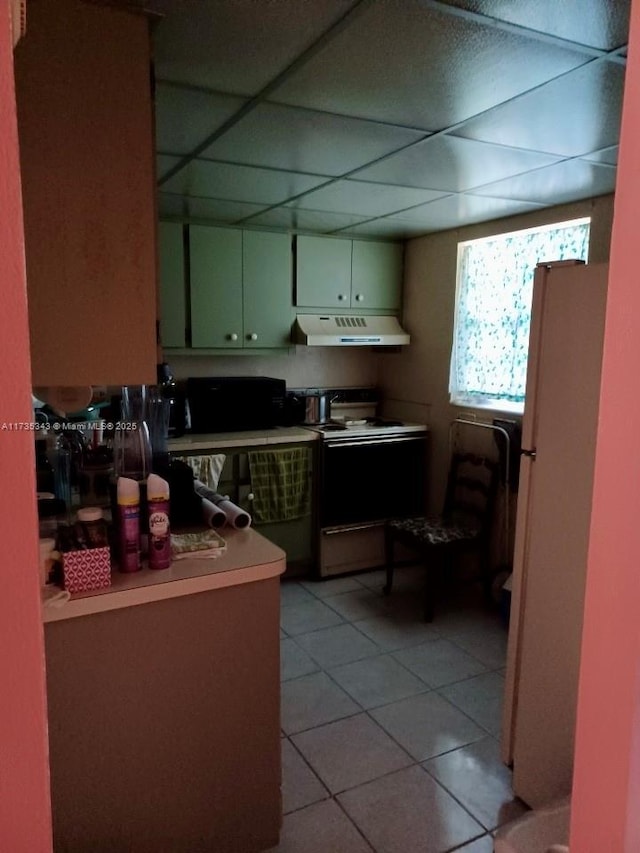 kitchen with white refrigerator, a drop ceiling, light tile patterned floors, and electric range