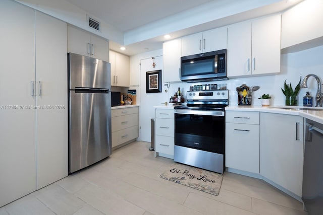 kitchen with stainless steel appliances, sink, and white cabinets