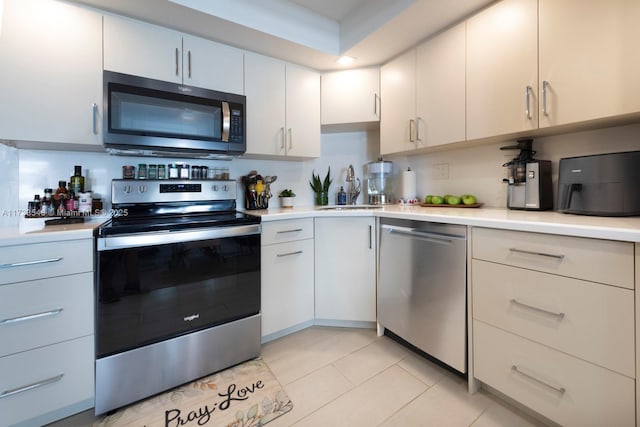 kitchen with white cabinetry, sink, light tile patterned floors, and stainless steel appliances