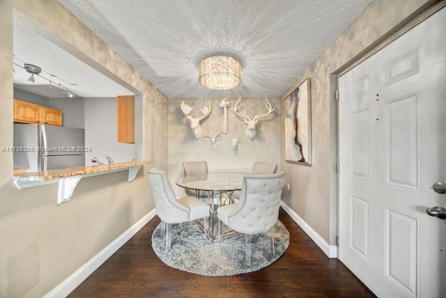 dining area with a textured ceiling and dark hardwood / wood-style flooring