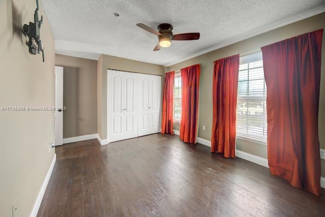 unfurnished bedroom with dark wood-type flooring, a textured ceiling, ceiling fan, and a closet