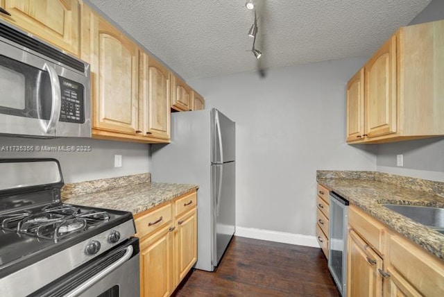 kitchen with dark wood-type flooring, appliances with stainless steel finishes, light stone counters, a textured ceiling, and light brown cabinets