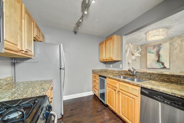 kitchen featuring stainless steel appliances, sink, light brown cabinets, and stone counters