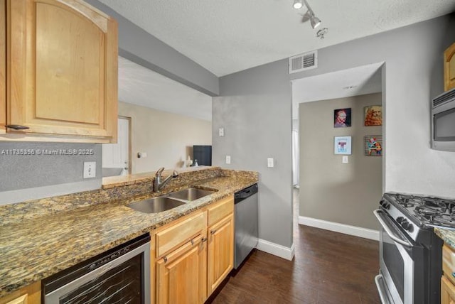 kitchen featuring sink, appliances with stainless steel finishes, light brown cabinetry, beverage cooler, and dark stone counters